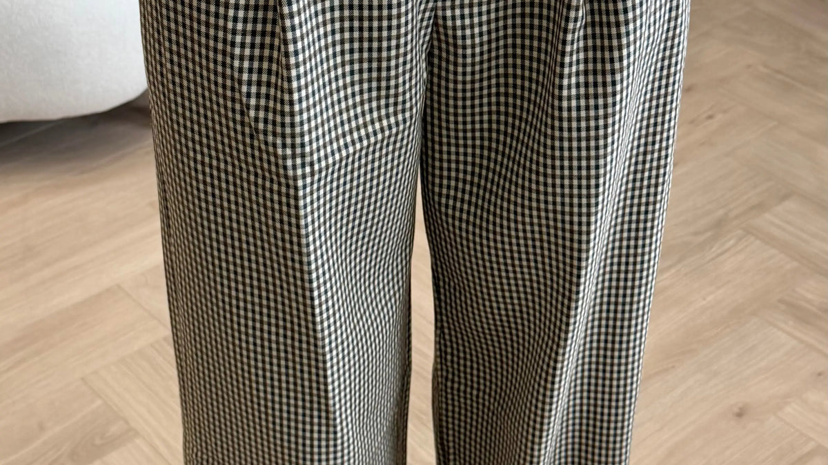 Pantalon à carreaux à coupe longue porté avec un haut blanc et des chaussures argentées.