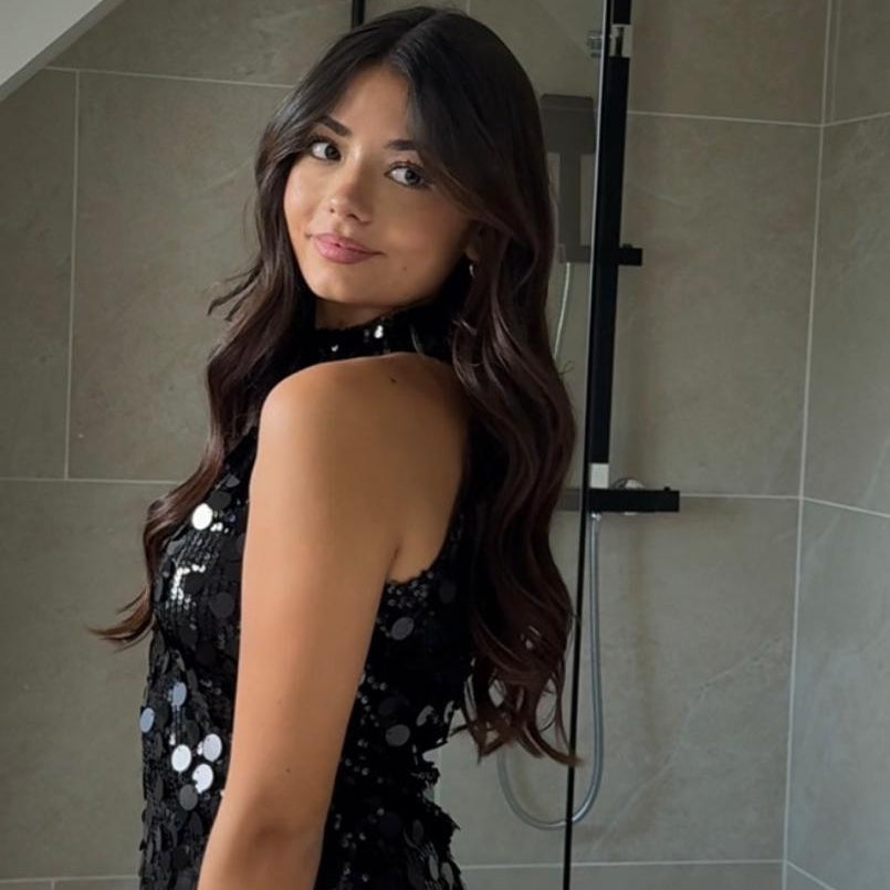 Femme portant une tenue noire sans manches à sequins et à col montant.