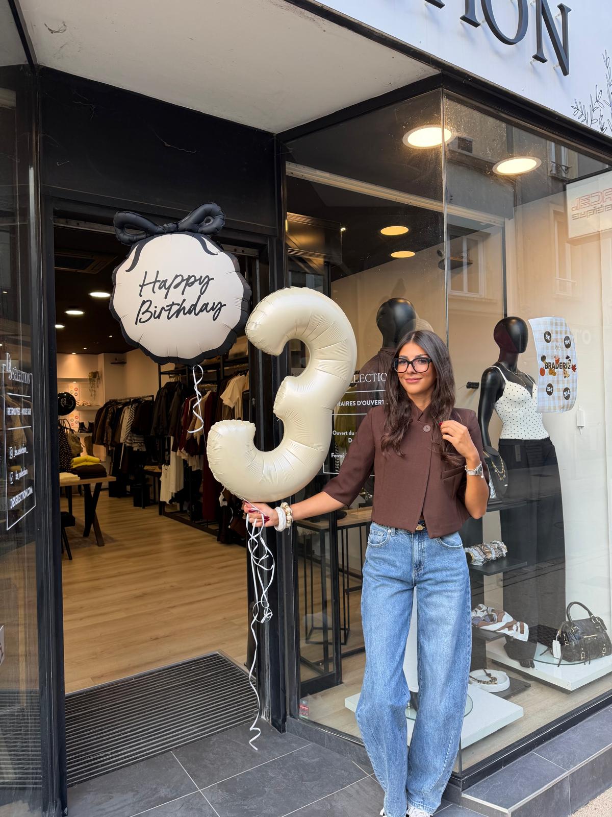 Femme devant la boutique DS Sélection à Cholet, tenant des ballons pour le troisième anniversaire du magasin.
