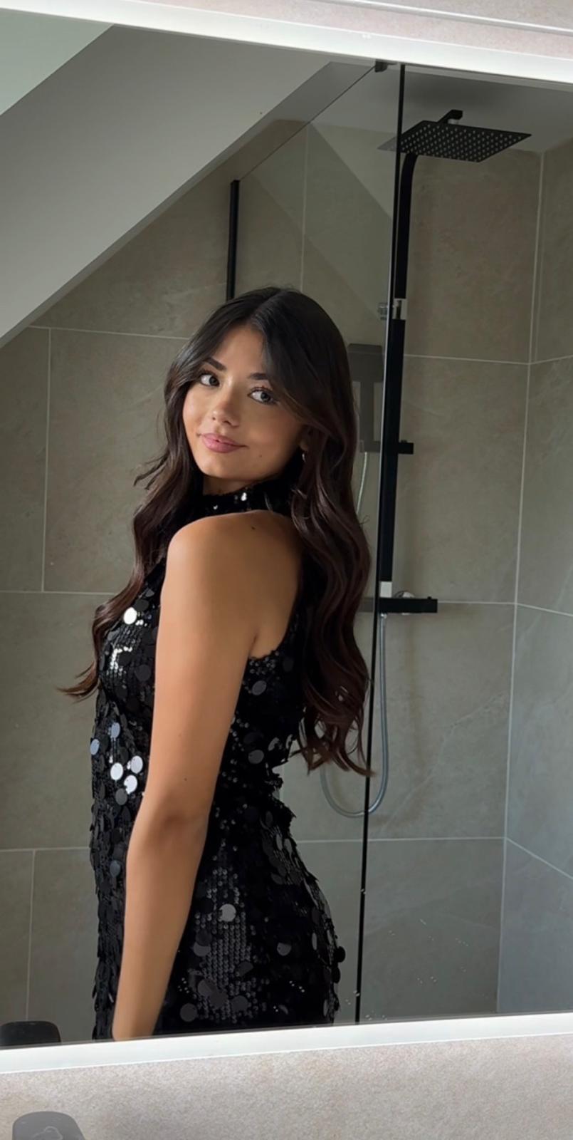 Femme portant une tenue noire sans manches à sequins et à col montant.